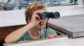 En speiderleder ser i kikkert.